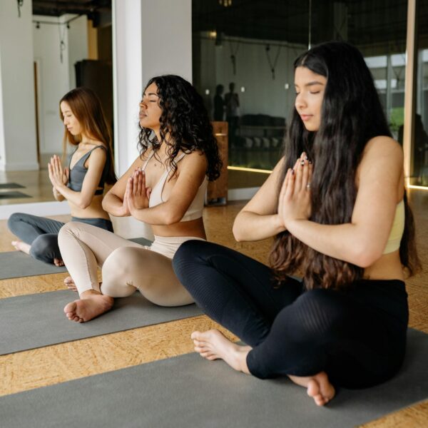 three women in prayer pose at yoga class