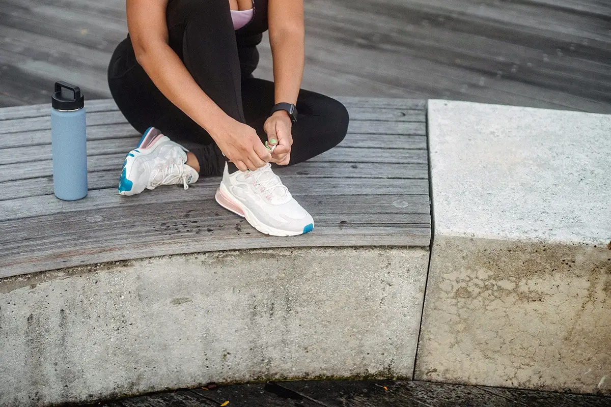 woman tying shoes on walk 