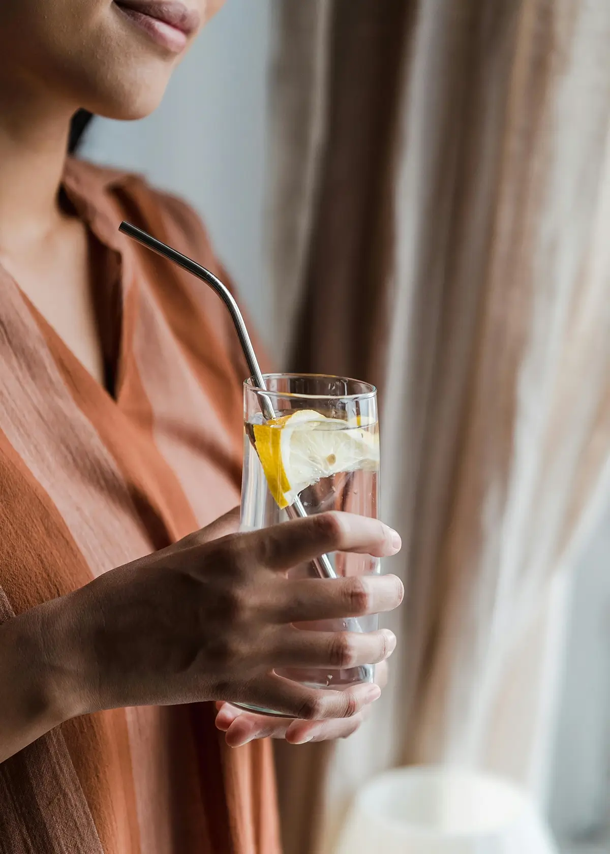 woman holding glass of water with lemon