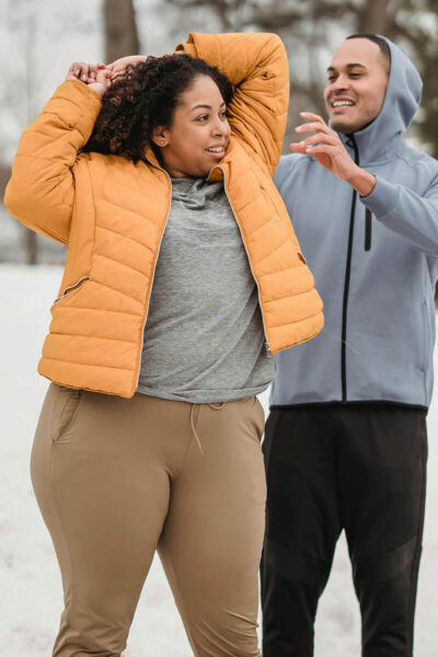 Couple in athletic clothes stretching in the snow