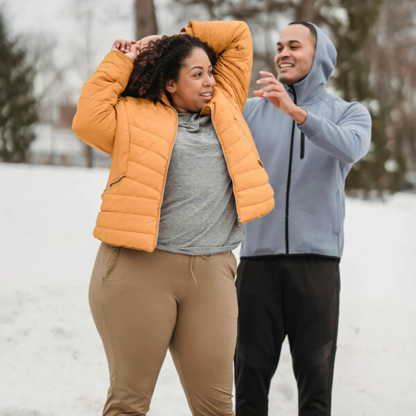 Couple in athletic clothes stretching in the snow